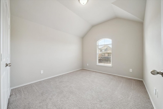 spare room with carpet floors and vaulted ceiling