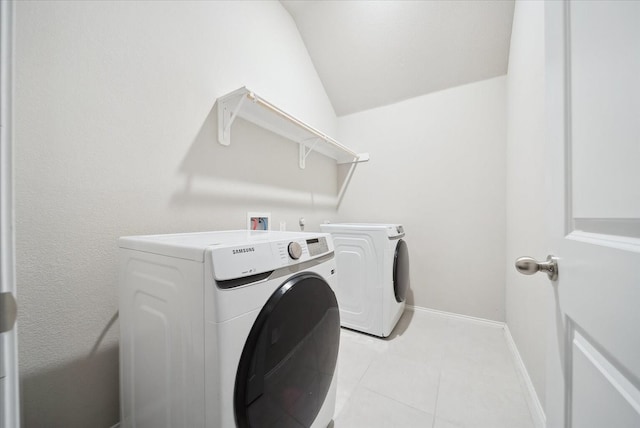 clothes washing area featuring washing machine and dryer and light tile patterned flooring