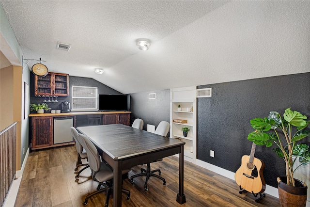 office area with vaulted ceiling, bar, dark wood-type flooring, a textured ceiling, and built in features