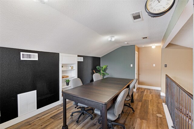 office area featuring lofted ceiling, wood-type flooring, a textured ceiling, and built in features