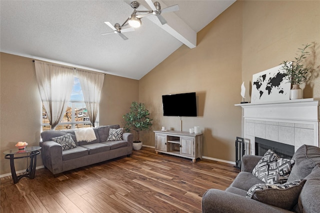 living room with a textured ceiling, a fireplace, vaulted ceiling with beams, ceiling fan, and dark hardwood / wood-style flooring