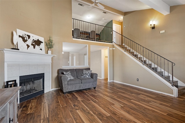 living room featuring a tile fireplace, beamed ceiling, ceiling fan, high vaulted ceiling, and dark hardwood / wood-style flooring