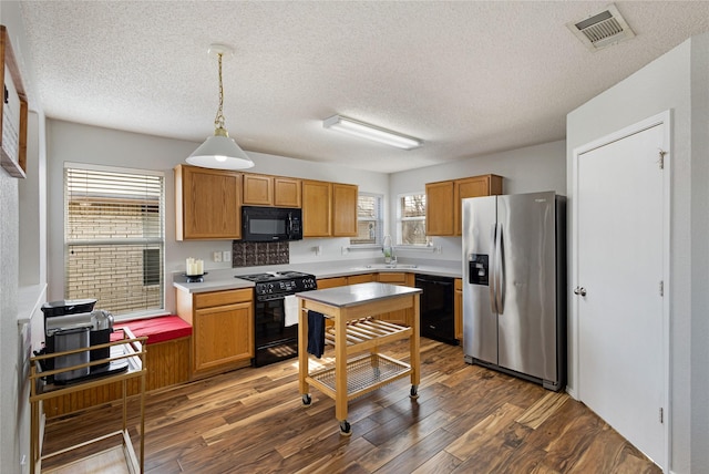 kitchen with a textured ceiling, dark hardwood / wood-style floors, decorative light fixtures, black appliances, and sink