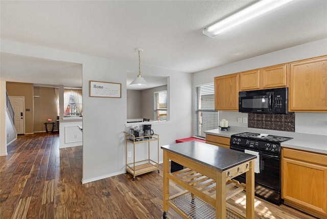 kitchen featuring black appliances, pendant lighting, and dark hardwood / wood-style flooring