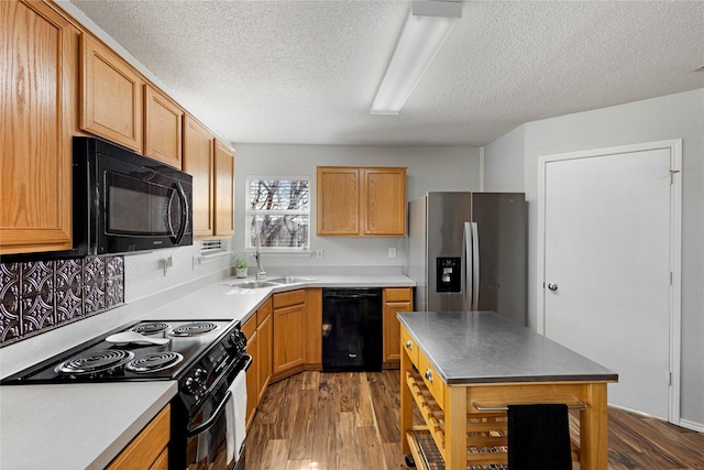 kitchen with dark wood-type flooring, a textured ceiling, black appliances, and sink