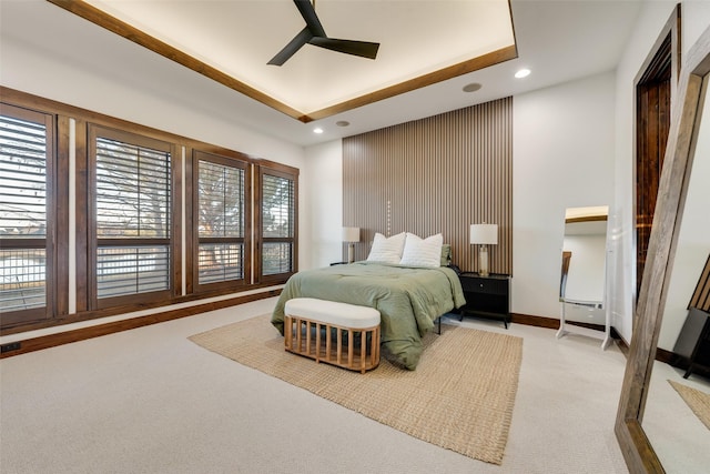 carpeted bedroom featuring ceiling fan and a tray ceiling