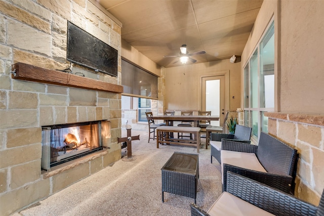 carpeted living room with ceiling fan and an outdoor stone fireplace