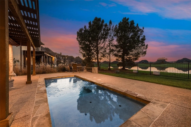 pool at dusk featuring a patio and a yard