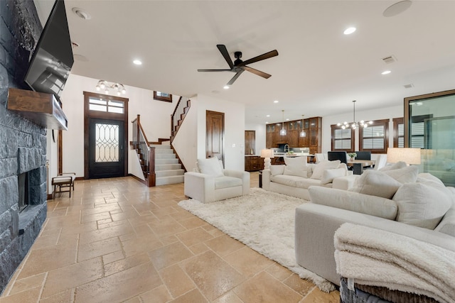 living room with a fireplace and ceiling fan with notable chandelier