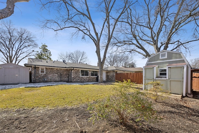 rear view of property featuring a lawn and a storage shed