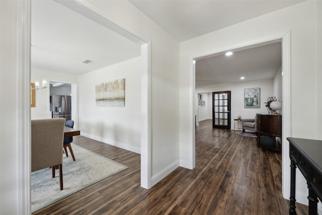 hallway with an inviting chandelier and dark hardwood / wood-style flooring