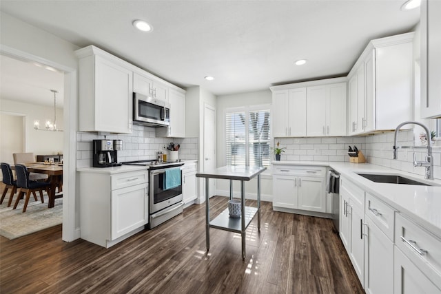 kitchen featuring stainless steel appliances, dark hardwood / wood-style floors, white cabinets, an inviting chandelier, and sink