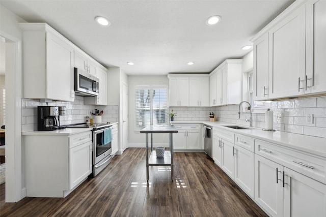 kitchen with stainless steel appliances, decorative backsplash, dark hardwood / wood-style floors, sink, and white cabinetry