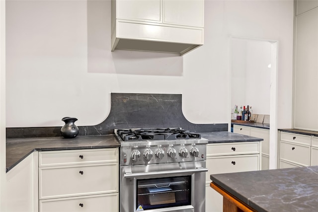 kitchen featuring decorative backsplash, stainless steel gas range, custom range hood, and white cabinetry