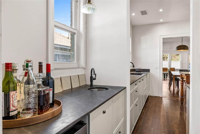 kitchen with sink, dark wood-type flooring, white cabinetry, and decorative light fixtures