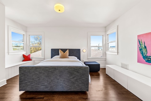 bedroom featuring multiple windows and dark hardwood / wood-style floors