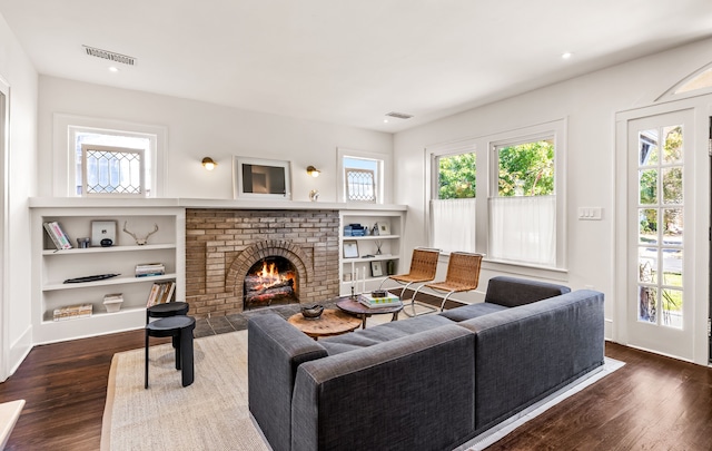 living room featuring a brick fireplace and dark hardwood / wood-style floors