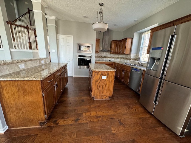 kitchen with decorative light fixtures, a center island, wall chimney exhaust hood, tasteful backsplash, and appliances with stainless steel finishes