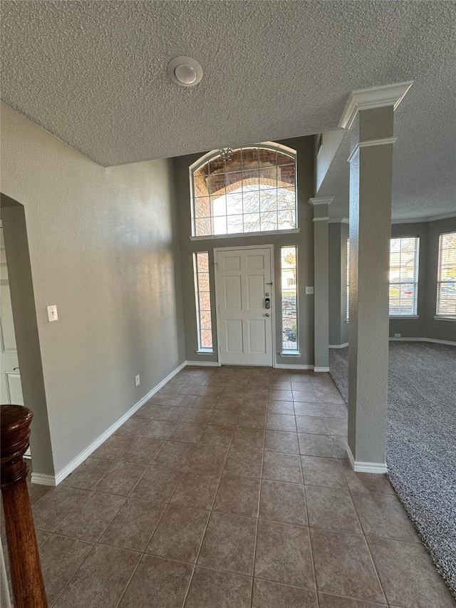 entryway featuring a towering ceiling and dark tile patterned flooring