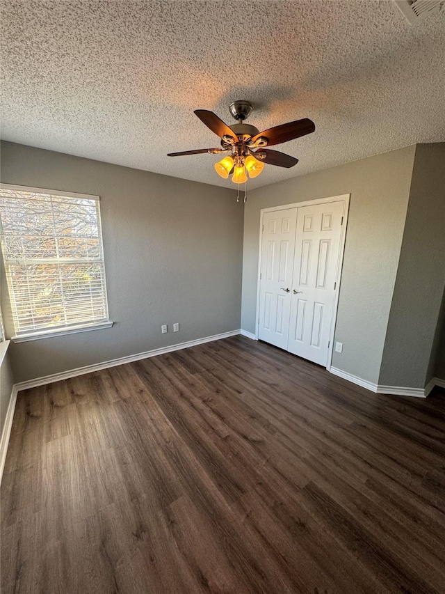 unfurnished bedroom featuring ceiling fan, a closet, a textured ceiling, and dark hardwood / wood-style floors