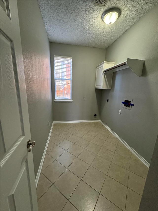 laundry room featuring a textured ceiling, electric dryer hookup, washer hookup, cabinets, and light tile patterned floors