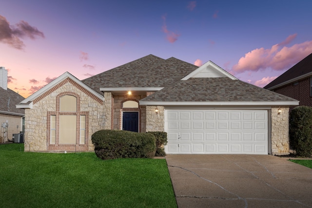 view of front of home featuring a garage, central air condition unit, and a lawn