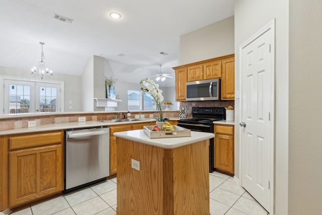 kitchen with appliances with stainless steel finishes, tasteful backsplash, vaulted ceiling, a kitchen island, and sink