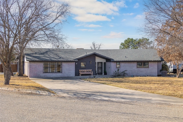 ranch-style home featuring central air condition unit and a front lawn