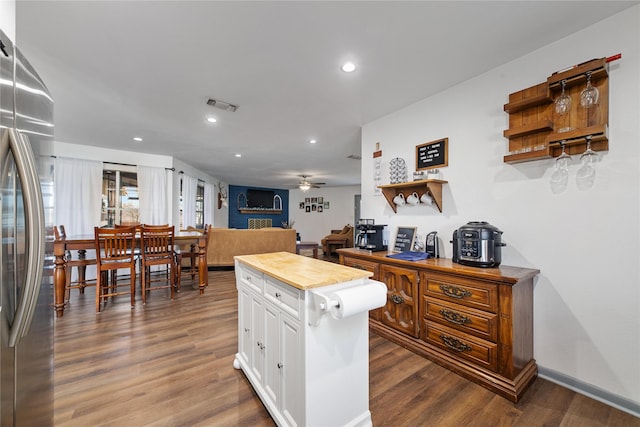 kitchen featuring stainless steel refrigerator, wood counters, dark wood-type flooring, a kitchen island, and white cabinetry