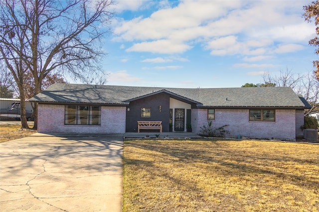 ranch-style house featuring central air condition unit, a front yard, and a garage