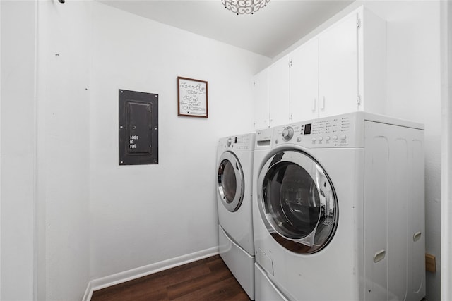 clothes washing area with electric panel, dark hardwood / wood-style flooring, washer and clothes dryer, and cabinets