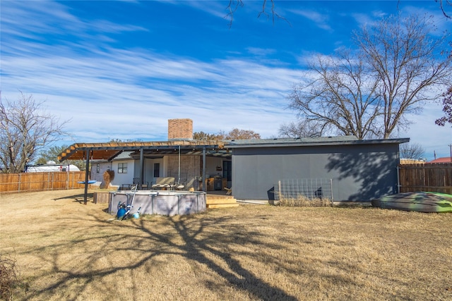 rear view of property with a covered pool and a yard