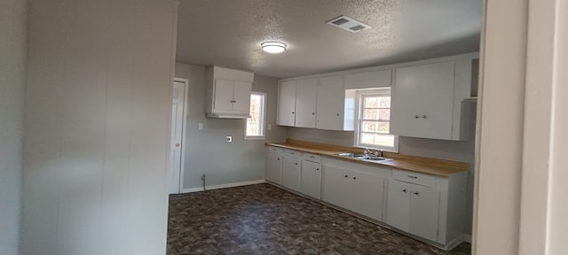 kitchen featuring sink, white cabinets, and a textured ceiling