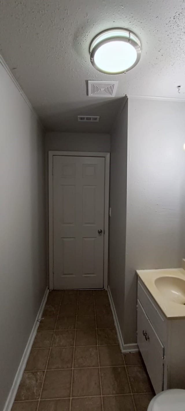 hallway featuring a textured ceiling, dark tile patterned flooring, and sink