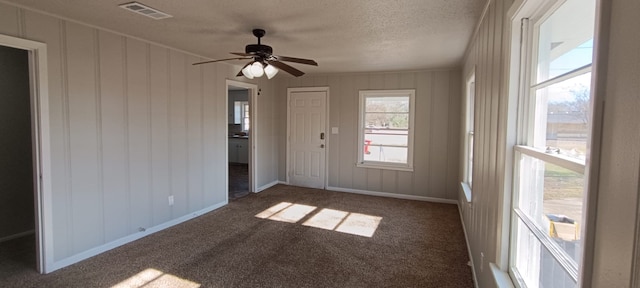 spare room with dark carpet, a textured ceiling, and ceiling fan