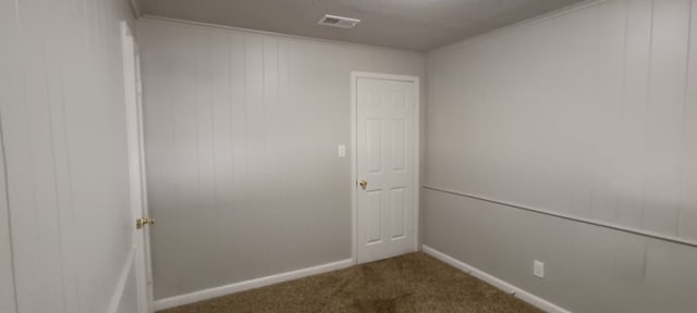 empty room featuring a textured ceiling, crown molding, and carpet