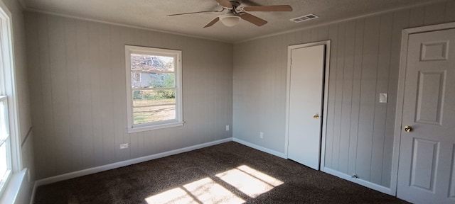 unfurnished bedroom with wood walls, ceiling fan, carpet, and ornamental molding