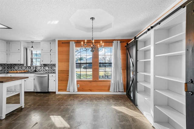 kitchen featuring a barn door, dishwasher, a notable chandelier, hanging light fixtures, and white cabinets