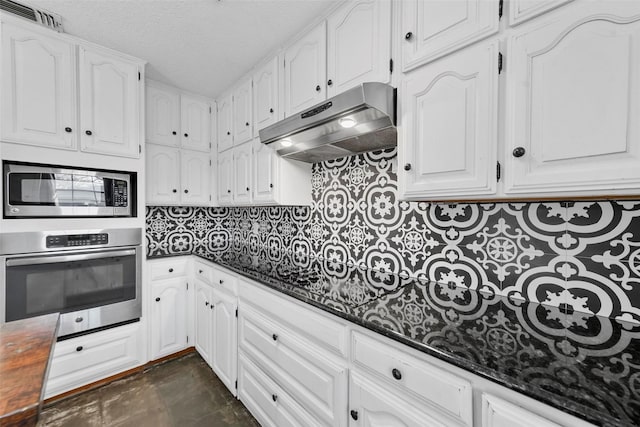 kitchen featuring backsplash, white cabinetry, stainless steel appliances, and dark stone counters