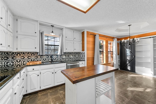 kitchen with decorative light fixtures, white cabinetry, sink, a chandelier, and stainless steel dishwasher