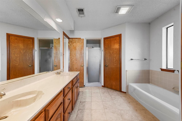 bathroom with a textured ceiling, vanity, and independent shower and bath