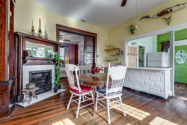 dining room with hardwood / wood-style flooring, ceiling fan, and a fireplace