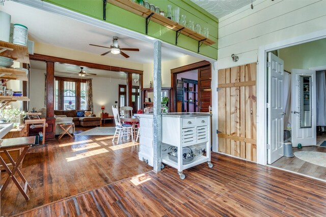 kitchen featuring wooden walls, hardwood / wood-style floors, and ceiling fan