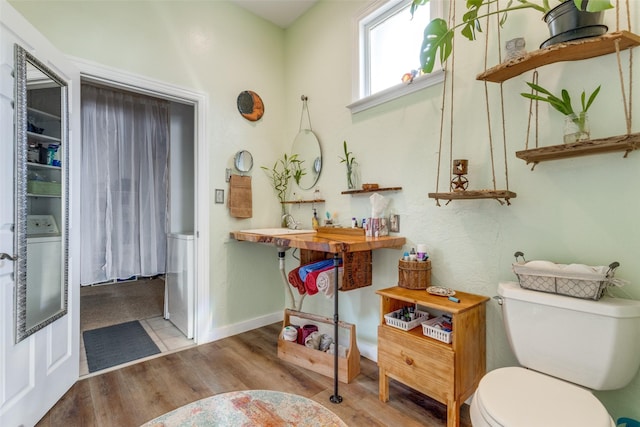 bathroom featuring toilet, hardwood / wood-style flooring, and washer / dryer