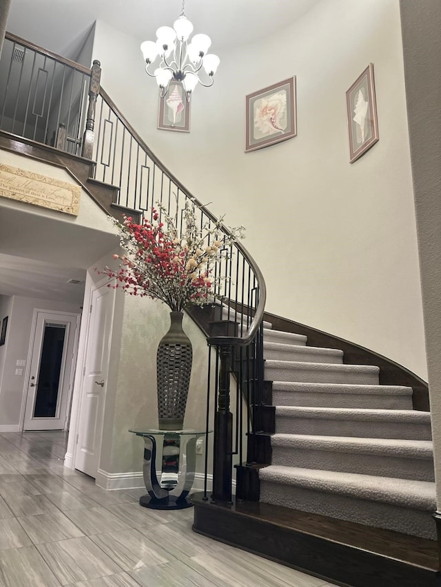 stairway with an inviting chandelier and a towering ceiling