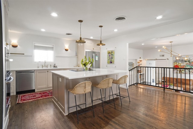 kitchen featuring dark hardwood / wood-style floors, pendant lighting, a center island, white cabinetry, and stainless steel appliances