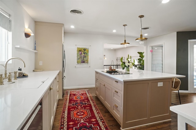 kitchen featuring pendant lighting, a kitchen bar, sink, dark hardwood / wood-style floors, and stainless steel refrigerator