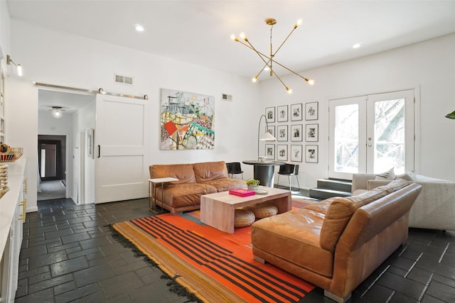 living room featuring a barn door, french doors, and a chandelier