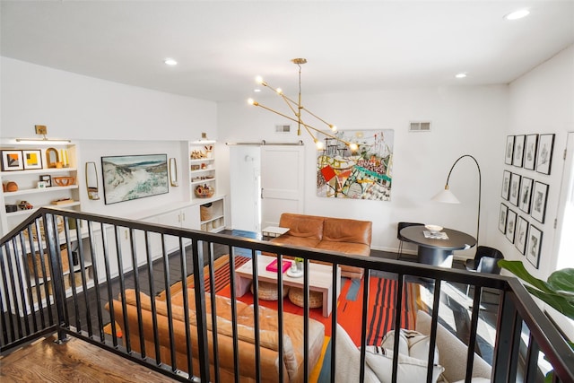 interior space with an inviting chandelier, a barn door, and hardwood / wood-style flooring