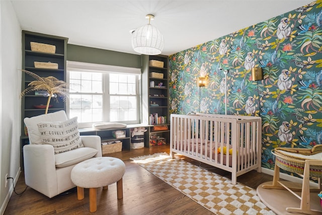 bedroom featuring a nursery area and dark wood-type flooring